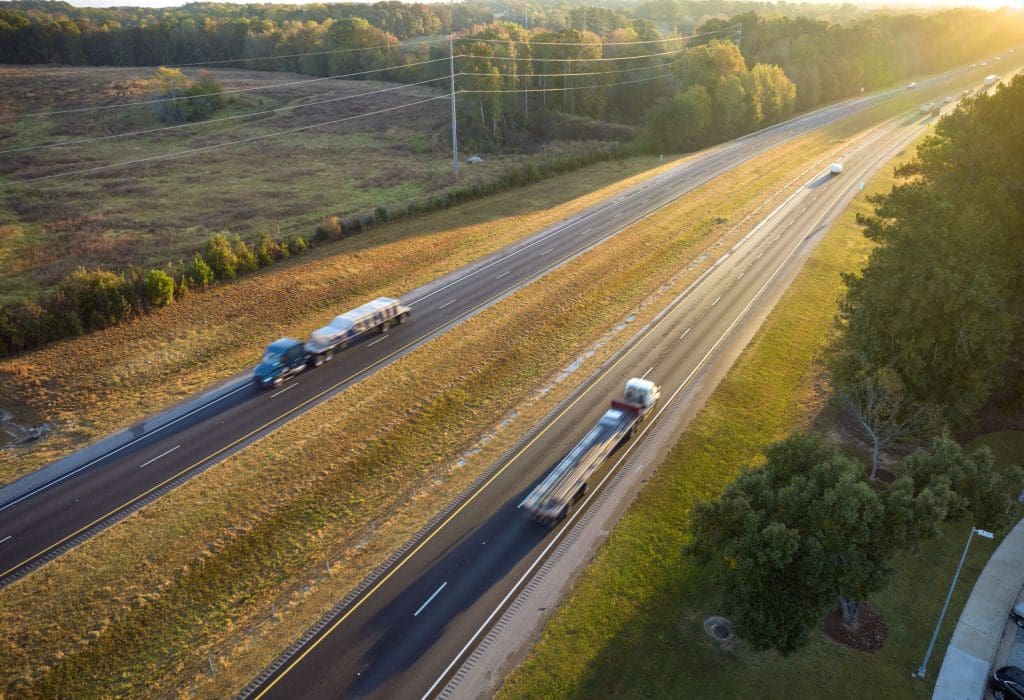 View from above of busy american highway with fast moving trucks and cars. Interstate transportation concept View from above of busy american highway with fast moving trucks and cars. Interstate transportation concept.
